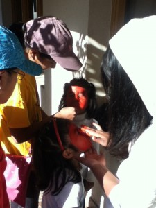 Our Little Pedacitos and Corazón chicas dressed as stop-lights. Victoria and Zamora are getting their faces painted.
